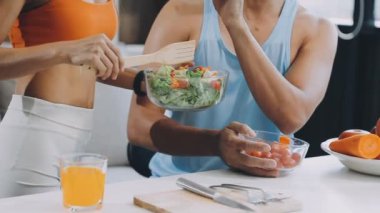 Spor giyimli genç bir çift sağlıklı kahvaltı hazırlıyor.