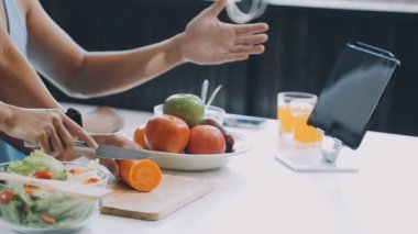 Sağlıklı yaşam tarzı ve yemek konsepti. Genç Asyalı kadın mutfakta salata hazırlıyor.