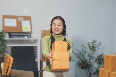 Girişim KOBİ küçük işletme girişimcisi önlük giyen Asyalı kadın dizüstü bilgisayar ve kutu kullanarak çevrimiçi müşterilere, çevrimiçi sme iş fikirlerine satış hazırlamak için siparişleri alır ve gözden geçirir.