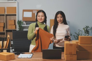 Girişim KOBİ küçük işletme girişimcisi önlük giyen Asyalı kadın dizüstü bilgisayar ve kutu kullanarak çevrimiçi müşterilere, çevrimiçi sme iş fikirlerine satış hazırlamak için siparişleri alır ve gözden geçirir.