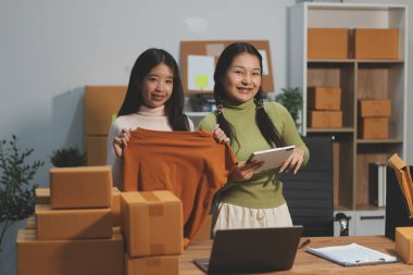 Girişim KOBİ küçük işletme girişimcisi önlük giyen Asyalı kadın dizüstü bilgisayar ve kutu kullanarak çevrimiçi müşterilere, çevrimiçi sme iş fikirlerine satış hazırlamak için siparişleri alır ve gözden geçirir.