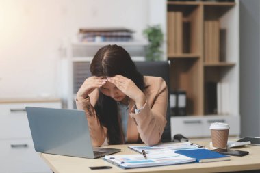Yorgun ve Asyalı bir kadının portresi ofiste vergi bilgisayarıyla çalışıyor. Üzgün, mutsuz, endişeli, depresyon ya da çalışan hayatı stres konsepti