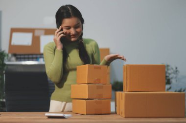 Girişim KOBİ küçük işletme girişimcisi önlük giyen Asyalı kadın dizüstü bilgisayar ve kutu kullanarak çevrimiçi müşterilere, çevrimiçi sme iş fikirlerine satış hazırlamak için siparişleri alır ve gözden geçirir.