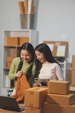 Girişim KOBİ küçük işletme girişimcisi önlük giyen Asyalı kadın dizüstü bilgisayar ve kutu kullanarak çevrimiçi müşterilere, çevrimiçi sme iş fikirlerine satış hazırlamak için siparişleri alır ve gözden geçirir.