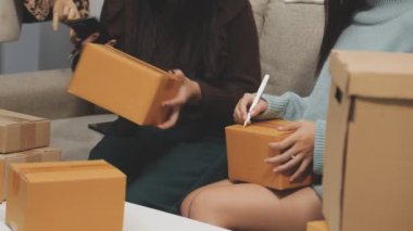 Kadın müşteri akıllı telefon kullanıyor ve mağazada kutu paketliyor.