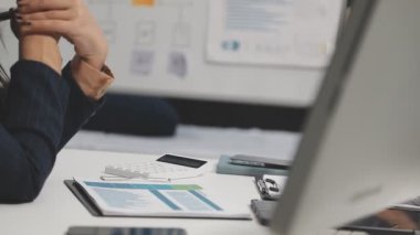 Dizüstü bilgisayarda çalışan ve elinde kalem tutan bir iş kadını.