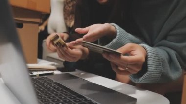 Alışveriş için laptop ve kredi kartı kullanan genç bir kadın.