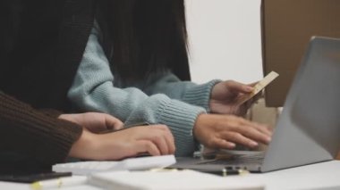 Genç Asyalı kadın kredi kartlarıyla online alışveriş yapıyor.