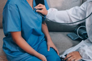 Doktor steteskop kullanıyor ve hastayı muayene ediyor.