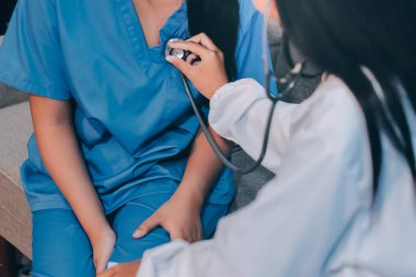 Doktor steteskop kullanıyor ve hastayı muayene ediyor.