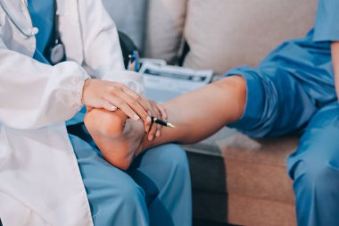 Doktor bir hastaya bacak tedavisi yapıyor.