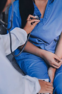 Doktor steteskop kullanıyor ve hastayı muayene ediyor.