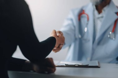 Klinikte hastanın elini sıkan olgun bir doktor.