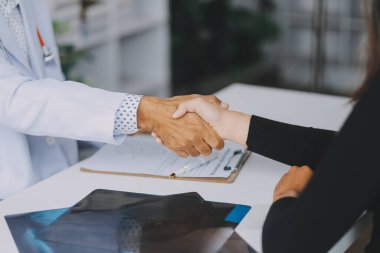 Klinikte hastanın elini sıkan olgun bir doktor.