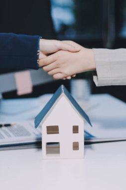 Gayrimenkul, sigortacı ya da avukatın çiftlerle el sıkışması. Konut kredisi veya sözleşme belgeleri imzalıyorlar.