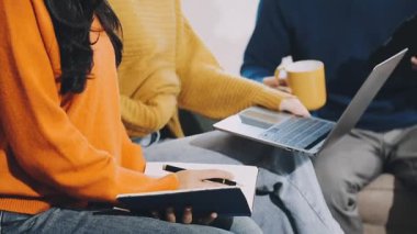 Genç adam, modern çatı katında çalışırken defter üzerinde yazı ve tablet kullanıyor.