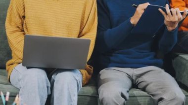 Kanepede otururken tablet kullanan genç Asyalı adam.