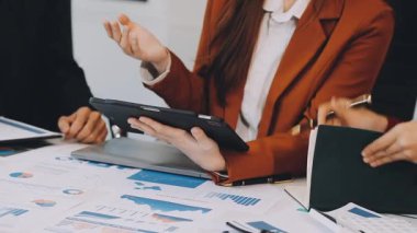 Dizüstü bilgisayarla çalışan ve ofiste mali raporları tartışan iş kadını.