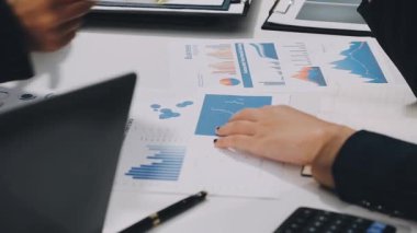 Modern ofisteki bilgisayarda finansal grafiği tartışan ve analiz eden işadamları.