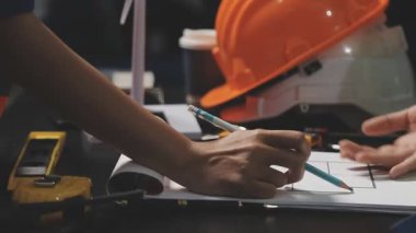 Üniformalı kadın mühendisin elinde planlar ve atölyedeki planlar, seçici bir odak noktası var.