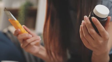 Yüzünde krem olan kozmetik şişeyi tutan bir kadın eli.