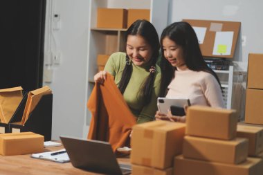 Girişim KOBİ küçük işletme girişimcisi önlük giyen Asyalı kadın dizüstü bilgisayar ve kutu kullanarak çevrimiçi müşterilere, çevrimiçi sme iş fikirlerine satış hazırlamak için siparişleri alır ve gözden geçirir.