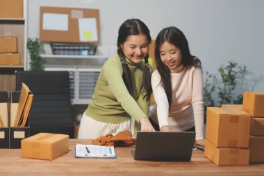 Girişim KOBİ küçük işletme girişimcisi önlük giyen Asyalı kadın dizüstü bilgisayar ve kutu kullanarak çevrimiçi müşterilere, çevrimiçi sme iş fikirlerine satış hazırlamak için siparişleri alır ve gözden geçirir.