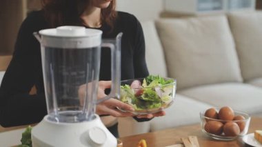 Kadın mutfakta taze smoothie hazırlıyor.