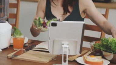 Kadın şef tablette taze sebze pişiriyor.