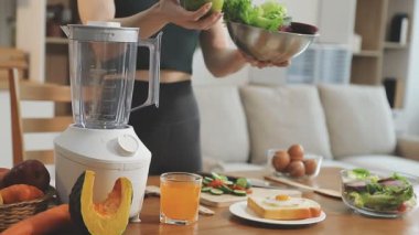 sağlıklı yaşam tarzı konsepti. Spor giyim bölümünde genç ve güzel bir kadın taze meyve püresi hazırlıyor..