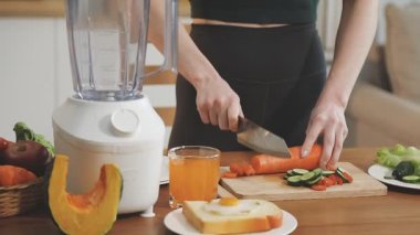 Genç bir kadın evde alkolden arınmak için smoothie hazırlıyor.