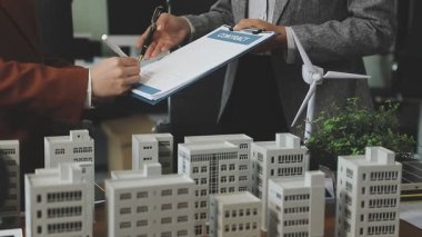 Mimari proje modeli üzerinde çalışan iş adamları.