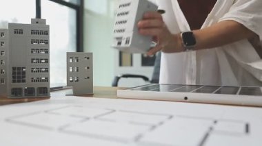 İnşaat planıyla birlikte ofis binasında çalışan mühendis.