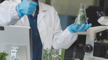 Laboratuvarda bir matara tutan bilim adamı.