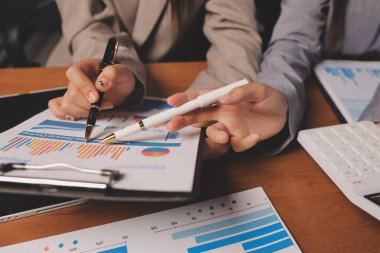 Group of confident business people point to graphs and charts to analyze market data, balance sheet, account, net profit to plan new sales strategies to increase production capacity.