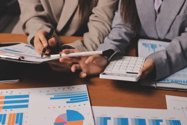 Group of confident business people point to graphs and charts to analyze market data, balance sheet, account, net profit to plan new sales strategies to increase production capacity.