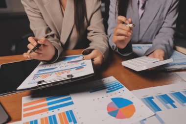 Group of confident business people point to graphs and charts to analyze market data, balance sheet, account, net profit to plan new sales strategies to increase production capacity.