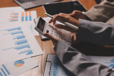 Group of confident business people point to graphs and charts to analyze market data, balance sheet, account, net profit to plan new sales strategies to increase production capacity.