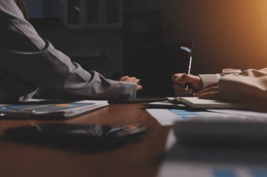 Group of confident business people point to graphs and charts to analyze market data, balance sheet, account, net profit to plan new sales strategies to increase production capacity.