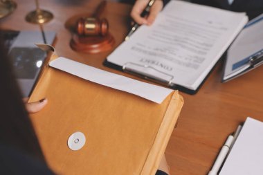 Ofisteki çekici genç avukat iş kadını ve avukatlar ofisdeki ahşap masada pirinç pullu kağıtları tartışıyorlar. Hukuk, hukuk hizmetleri, danışmanlık, Adalet ve emlak kavramı.