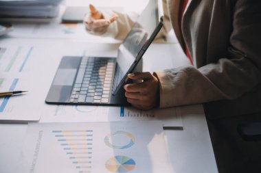 Two young Asian business woman talk, consult, discuss working with new startup project idea presentation analyze plan marketing and investment in the office.