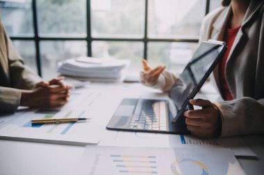 Two young Asian business woman talk, consult, discuss working with new startup project idea presentation analyze plan marketing and investment in the office.