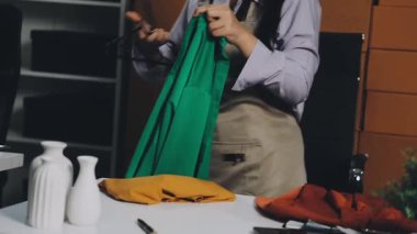 Yeşil elbiseli ve siyah gömlekli genç bir kadın. Elinde tahta bir tahta var.