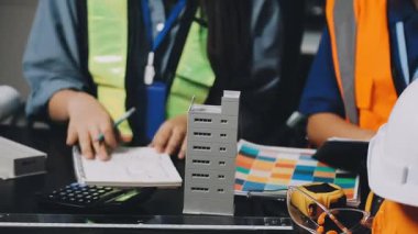 Arka planda güvenlik ekipmanı ve inşaat planıyla bina veya inşaat alanında çalışan mühendis veya mühendis veya işçi.