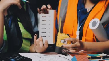 Üniformalı genç bayan mimar bir inşaat alanının planlarını kontrol ediyor.