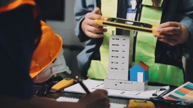 Masada mavi gömlekli, beyaz gömlekli genç bir kadın duruyor ve bir planla çalışıyor..