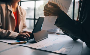 Two young Asian business woman talk, consult, discuss working with new startup project idea presentation analyze plan marketing and investment in the office.
