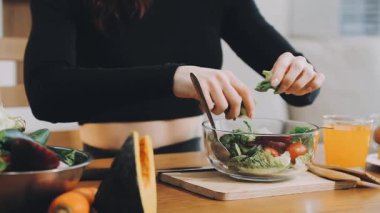 Kadın mutfakta taze sebze salatası hazırlıyor.