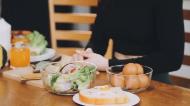 Kadın masada sağlıklı bir kahvaltı yapıyor.