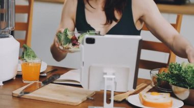 Genç ve güzel bir kadın modern mutfakta sağlıklı salata yapıyor..